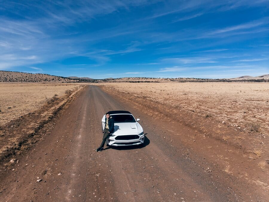 Man Traveling By Car On The Desert Road